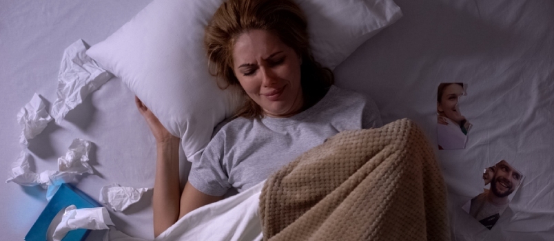 Plačúca žena ležiaca v posteli s tkanivami, roztrhaná fotografia bývalého priateľa vedľa