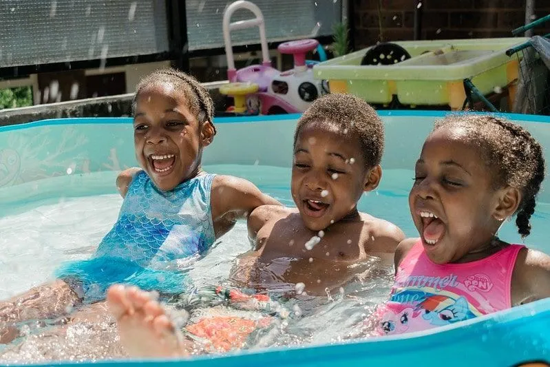 Tre barn skrattar och njuter i den rena plaskdamm