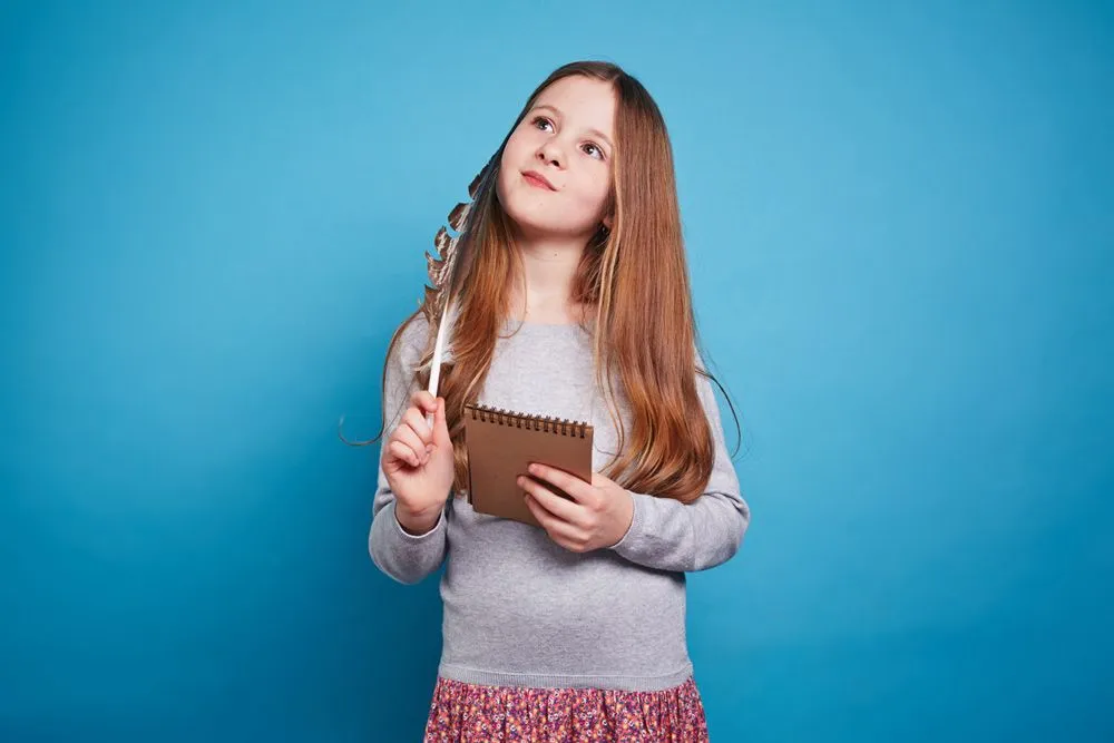 En jente ser gjennomtenkt ut med notatblokken sin mot en blå bakgrunn.