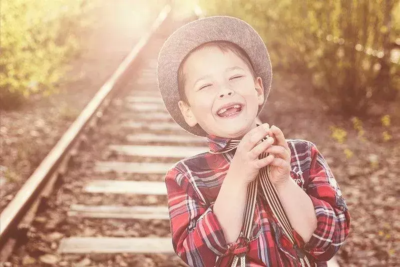 Gutt på et jernbanespor som ler av froskespill.