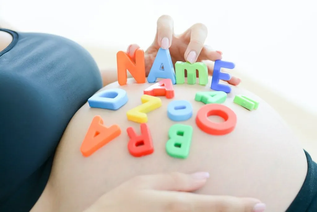 Vordende mor med bokstavblokker som staver " navn" på magen.