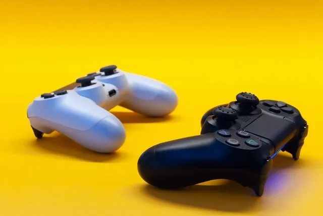 Белые и черные игровые контроллеры на желтом фоне