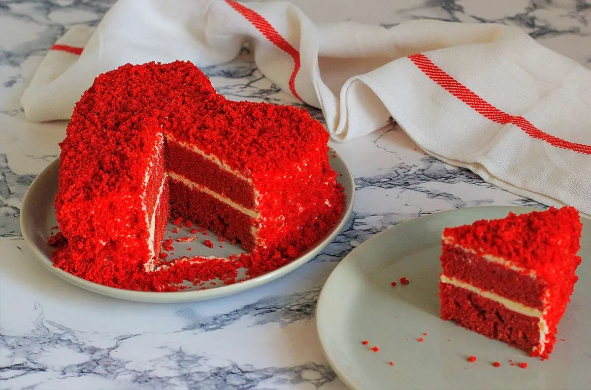 Червоний оксамитовий торт у формі червоного серця з тортом, розсипаним на глазурі.