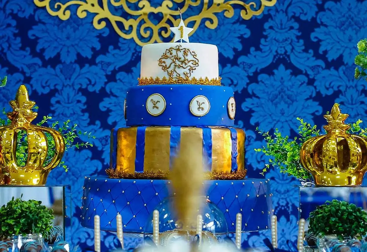 Розкішний багатоярусний торт у синьо-білій глазурі із золотими прикрасами.