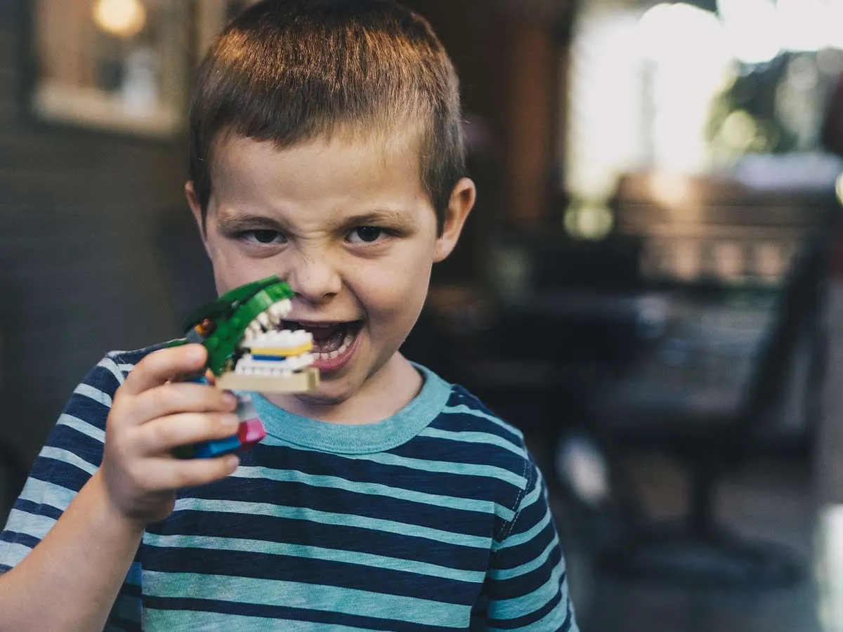 Ung gutt leker med en dinosaurleke og lager et ansikt som om han brøler.