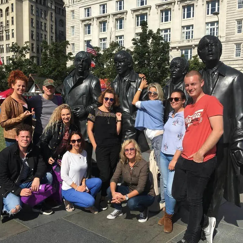Emberek pózolnak a The Beatles szobraival Liverpoolban.