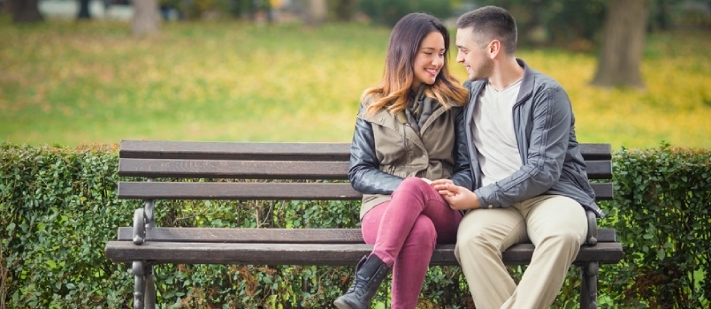Laiminga jauna įsimylėjusi pora sėdi ant suoliuko parke