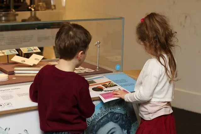 en liten jente og gutt på bank of england museum ser på en utstilling 