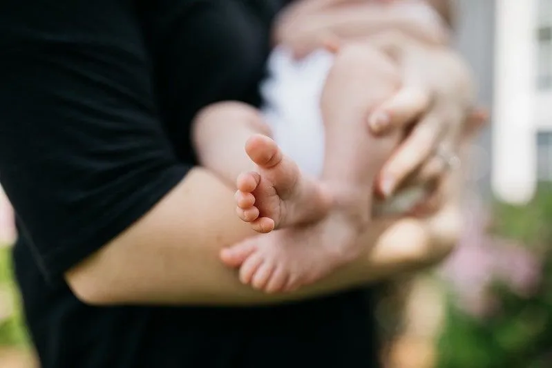 Краката на бебето навън, докато го държи родител.