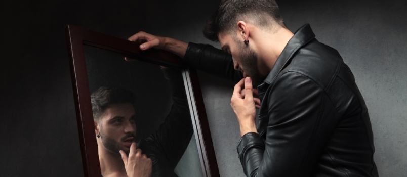 ნარცისი სექსუალური ახალგაზრდა მამაკაცი სარკეში აღფრთოვანებულია და ტუჩებს თითებს ეხება