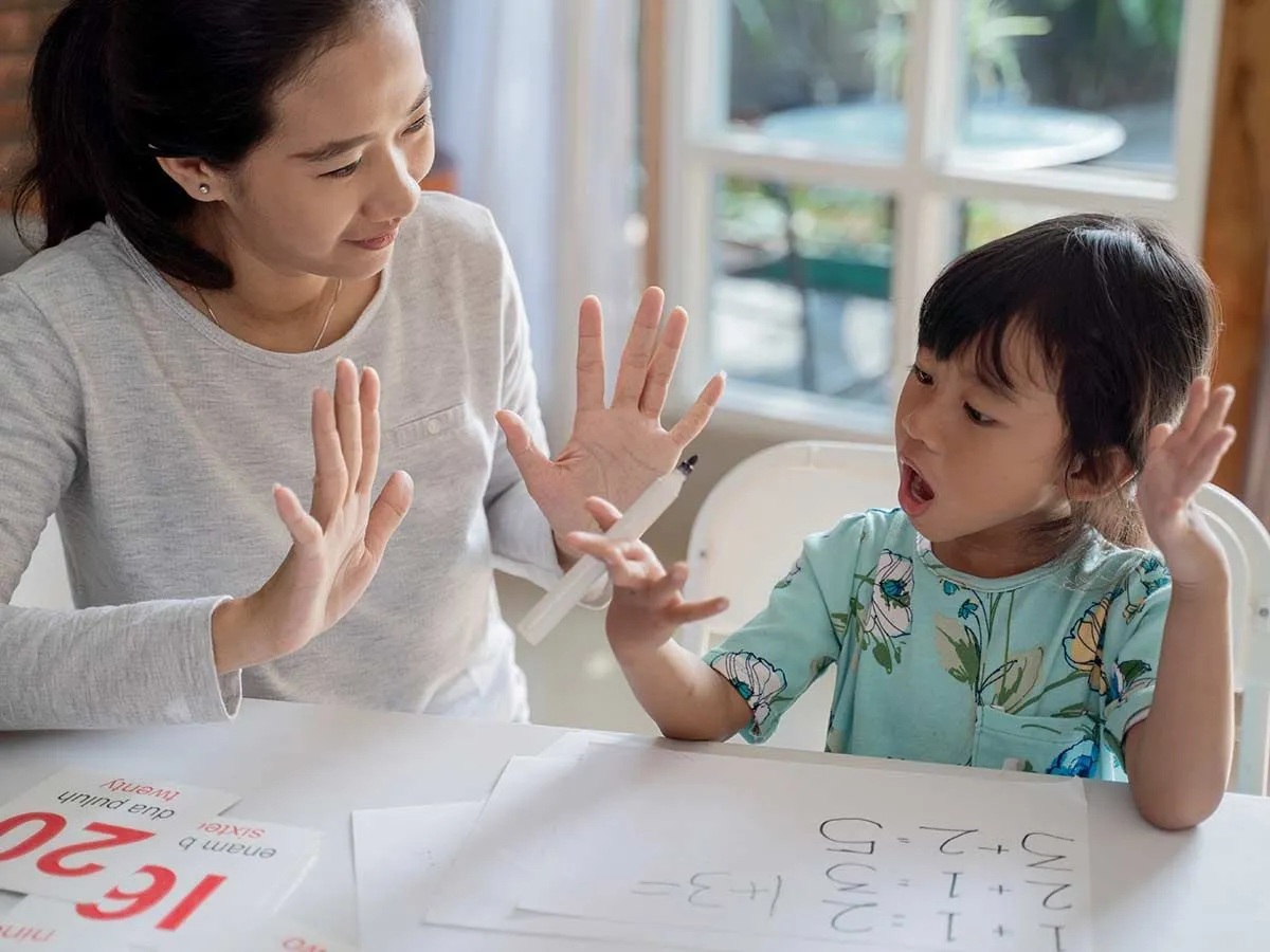 Madre e hija están sentadas a la mesa contando con los dedos para aprender a redondear números.