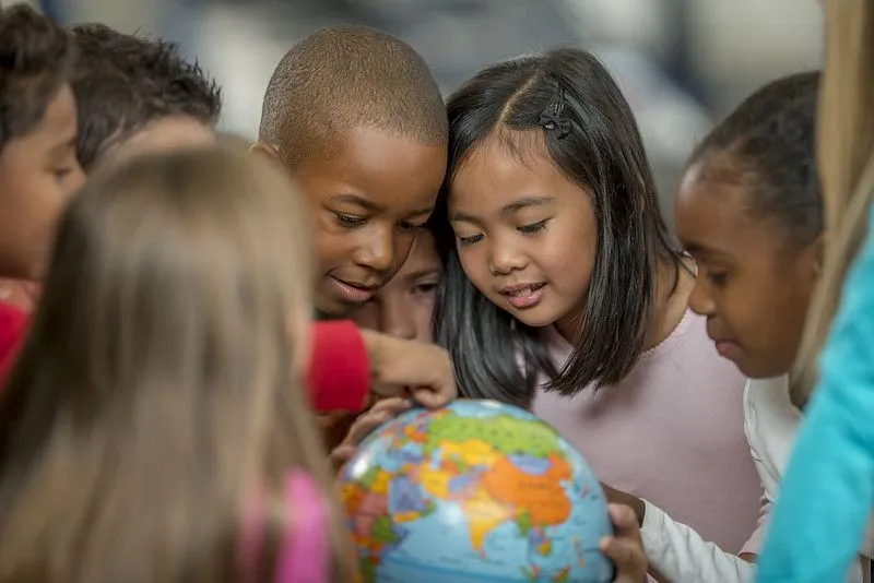 Gruppe barn som ser på en jordklode for å lære om mangfold.