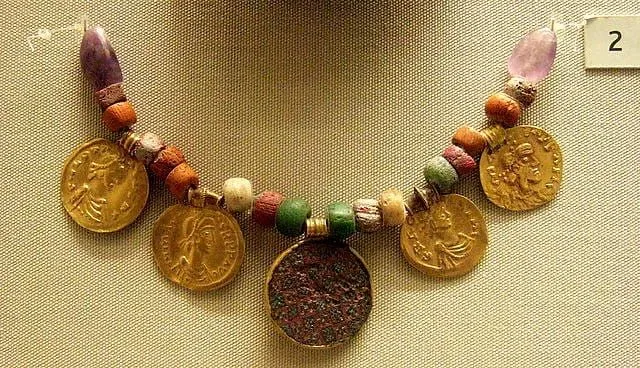 Et angelsaksisk kjede, laget av perler og store gullmynter, hengende utstilt i et museum.
