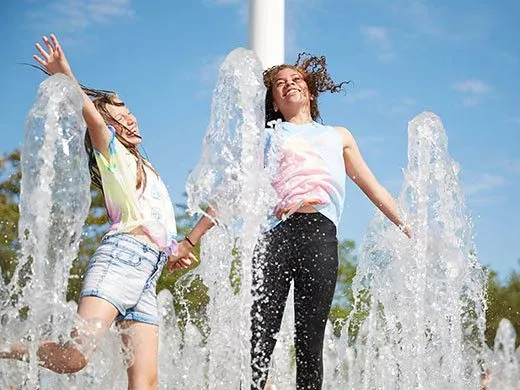 to jenter som plasker rundt i vannstråler på en varm dag