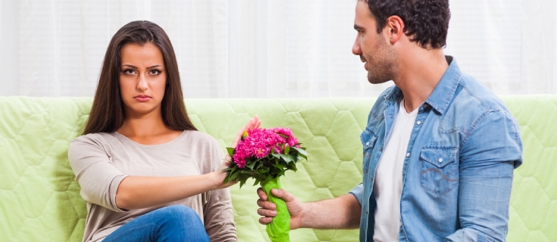 Jauna pora sėdi prie sofos namuose. Moteris pyksta, vyras dovanoja gėlių knygelę Moterys ignoruoja, kad priimtų