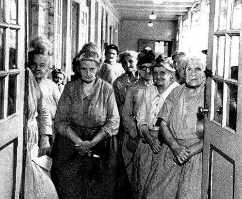 ქალები, რომლებიც დგანან ვიქტორიანული სამუშაო სახლის დერეფანში.