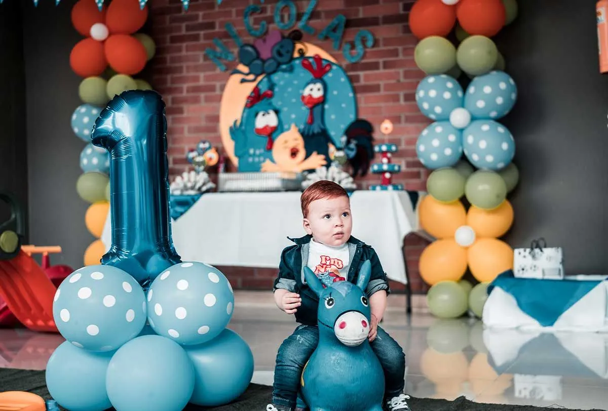 Mažylis per savo pirmąjį gimtadienį sėdėjo ant žaislinio asilo, puošdamasis balionais.