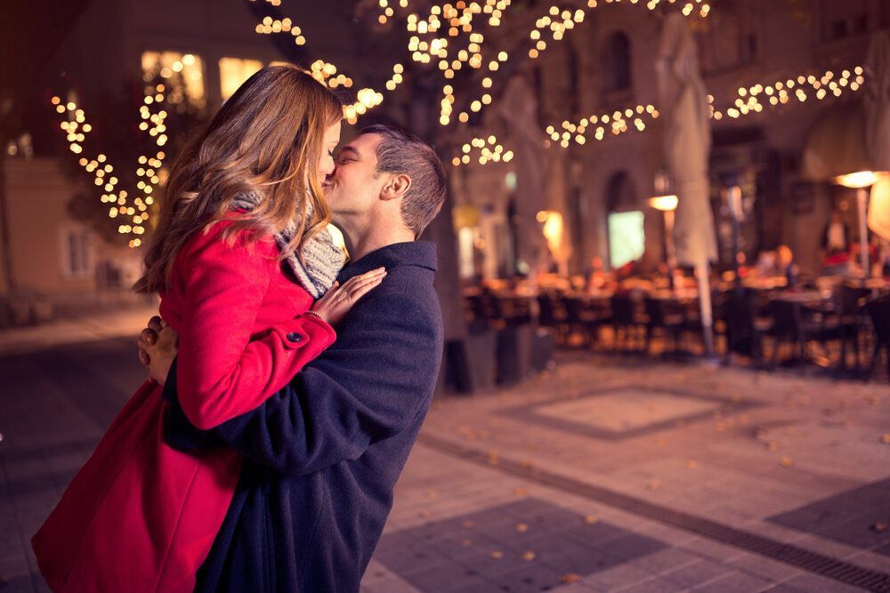 Cuplu care se sărută pasional cu lumini frumoase în fundal
