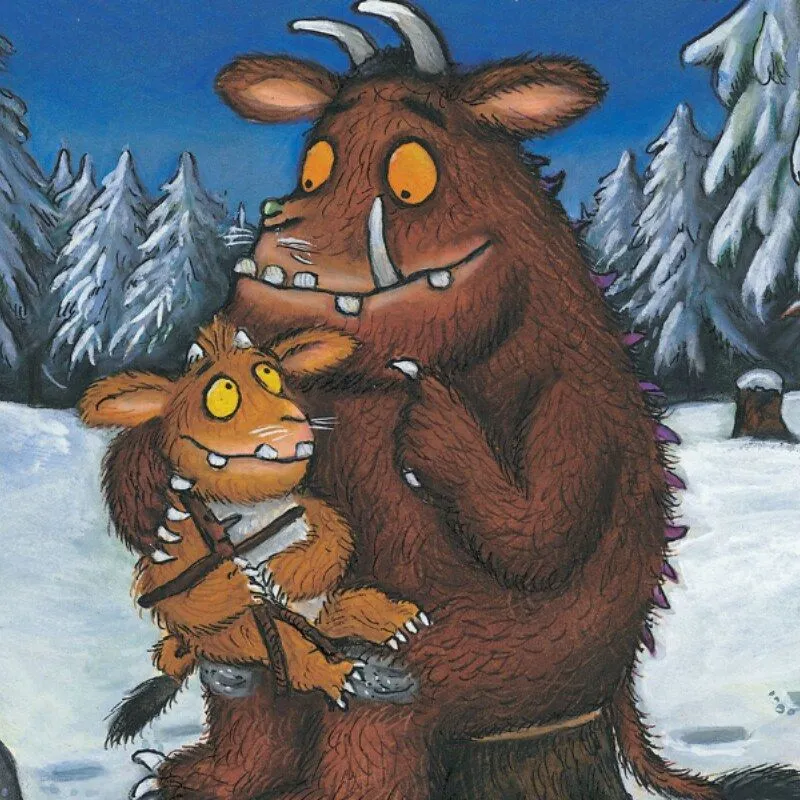 En voksen Gruffalo satt på en trestubbe i en snødekt skog, med en ung Gruffalo på fanget.