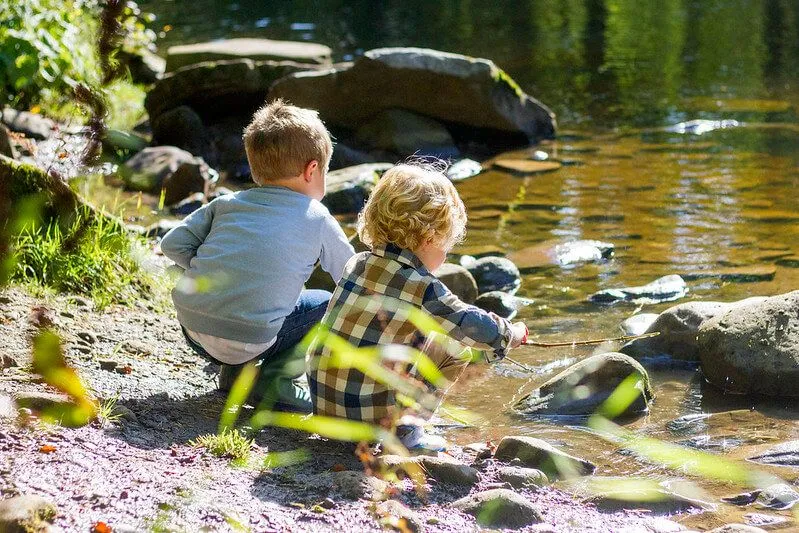 Barn som leker på elvebredden og leker med steiner og forteller steinspill