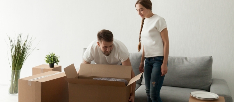Jovens cônjuges carregando caixas se mudando para um novo apartamento