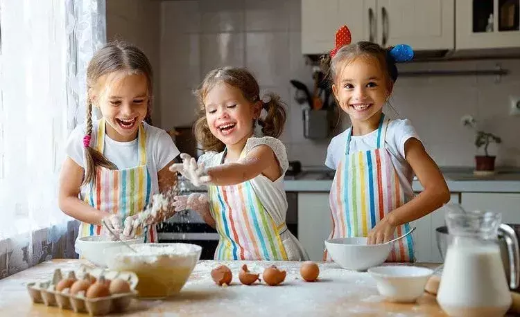 Три дівчини насолоджуються під час випічки торта