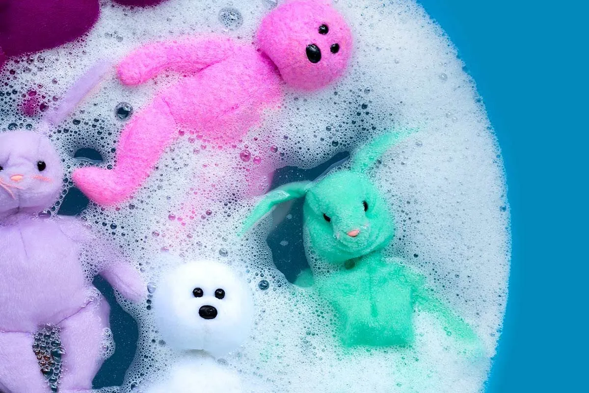 Fargerike leketøysbjørner som bløtlegger i en balje med såpevann.