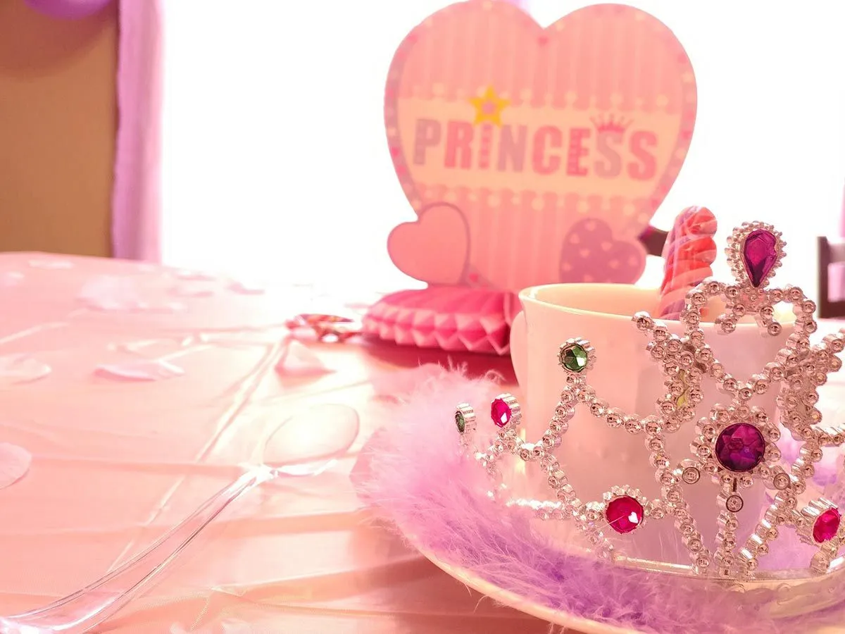 Prinsesse festborddekning, rosa bordtrekk, rosa dekorasjoner og tiara.
