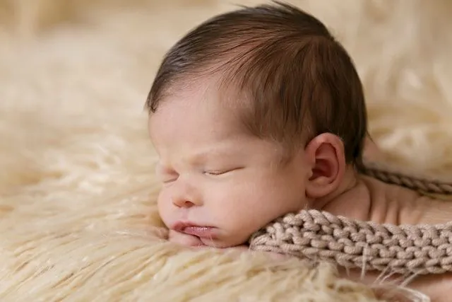 Liten jentebaby i 1800-talls teppe som sover.