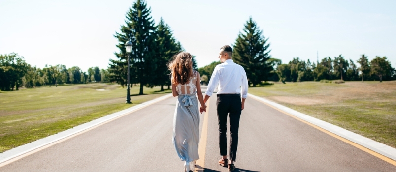 Laiminga nuotaka ir jaunikis susikibę už rankų eina keliu po vestuvių ceremonijos. Vaizdas Iš nugaros