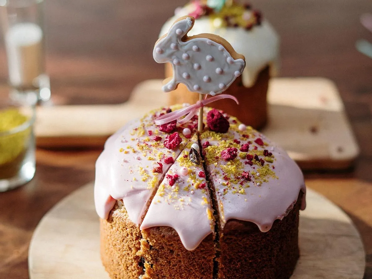 Kake med rosa glasur og en kjeks formet som en kanin stukket på en pinne på toppen.