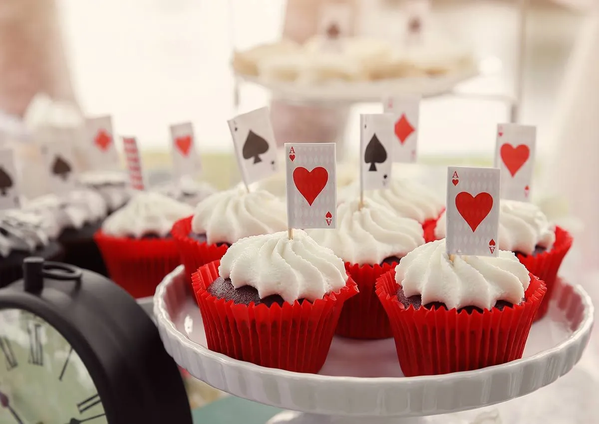 Cupcakes i røde etuier med dekorasjoner inspirert av spillekort.