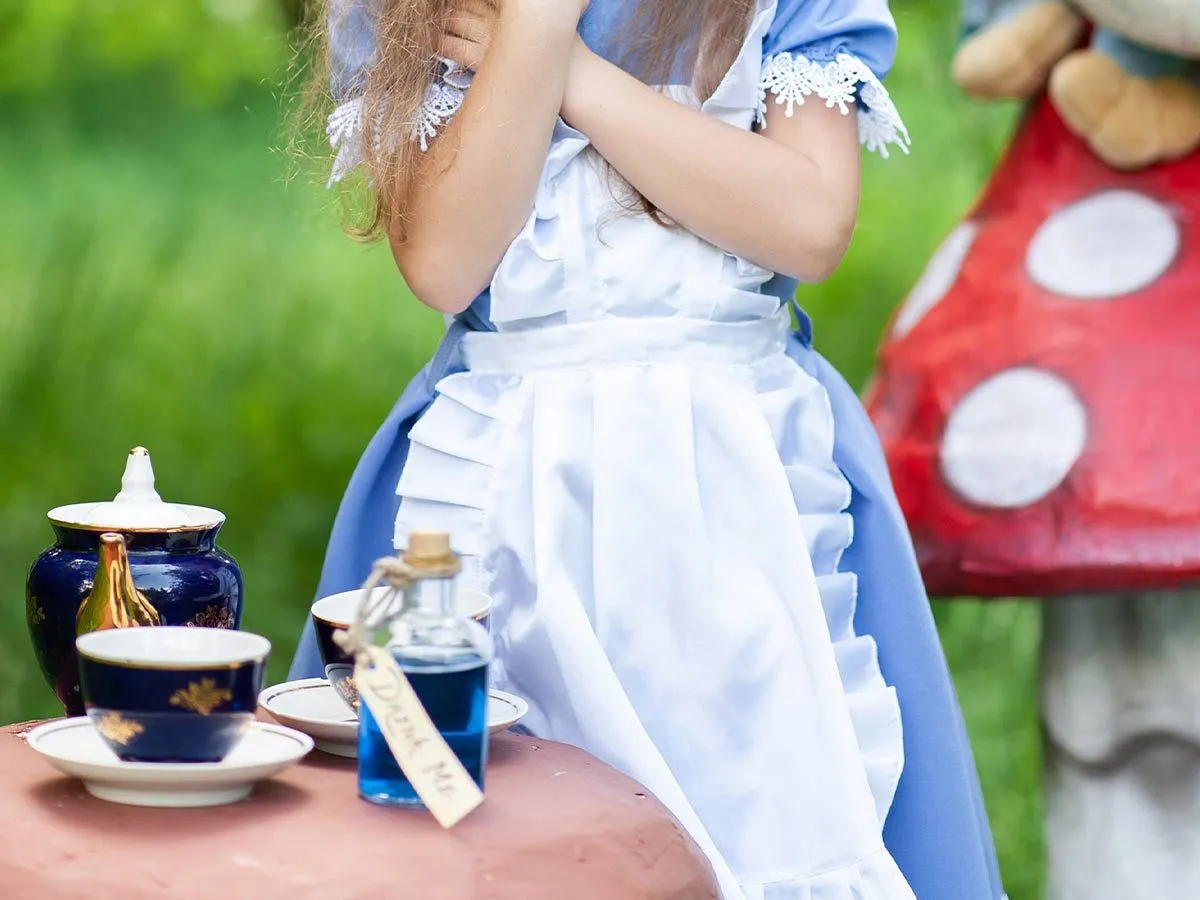 Jente utkledd som Alice i Eventyrland som spiller ut Madhatters teselskap.