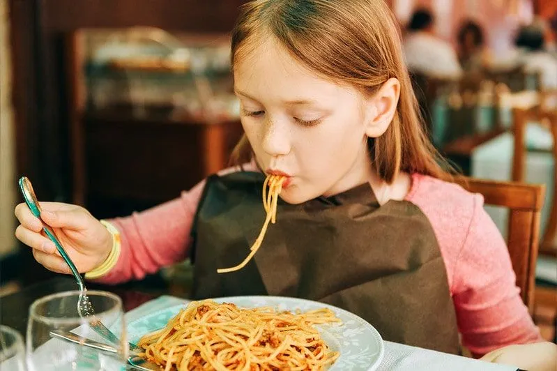 Dívka jí špagety v restauraci.