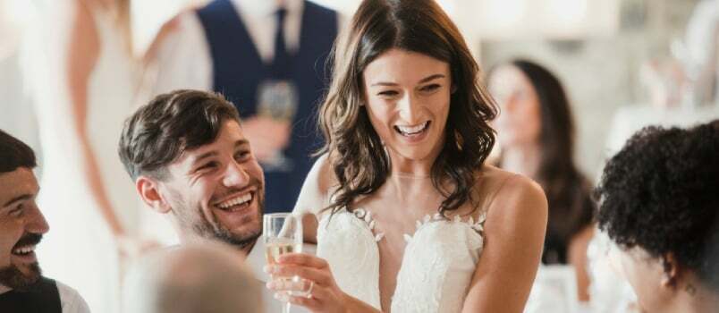 Mirii fericiți socializează cu invitații la recepția lor de nuntă.