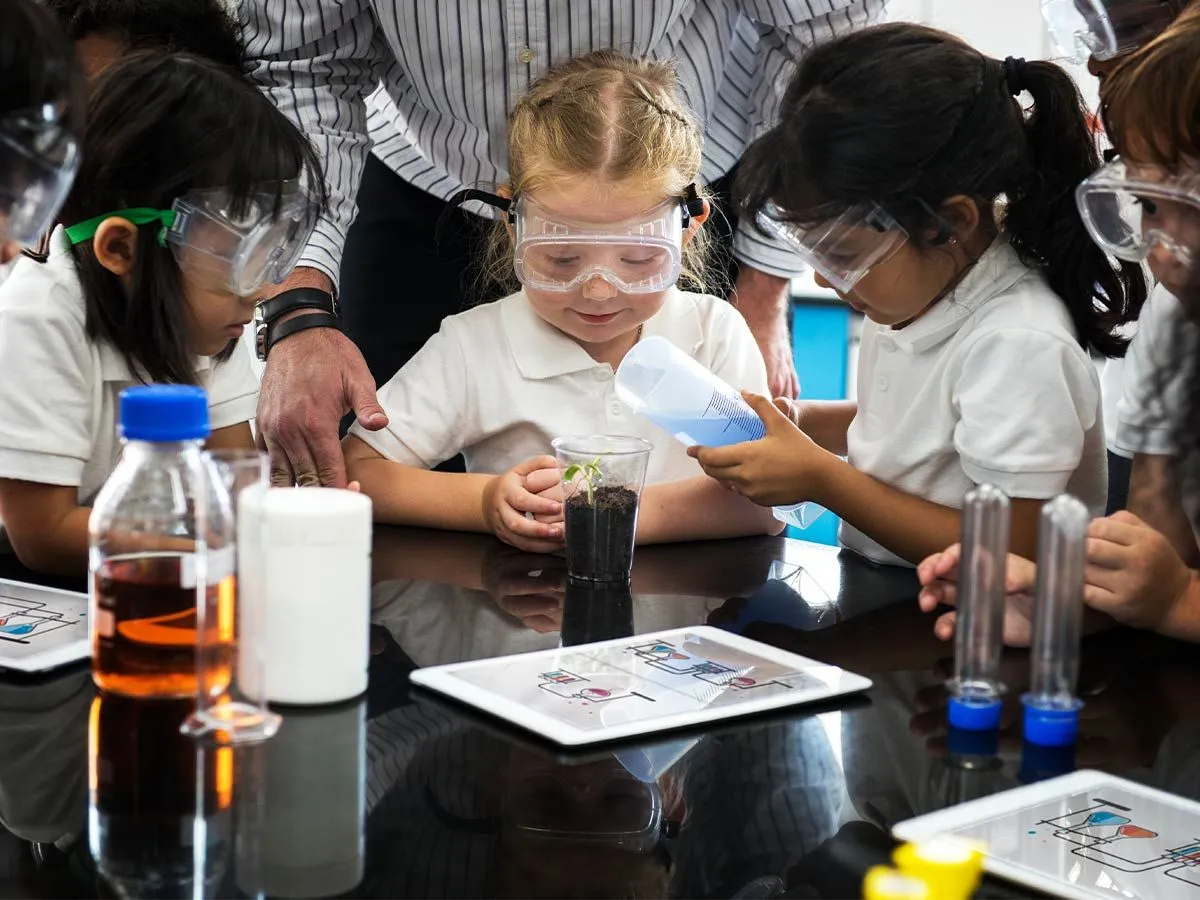 I bambini in età prescolare si sono seduti a un tavolo indossando occhiali mentre facevano esperimenti scientifici.