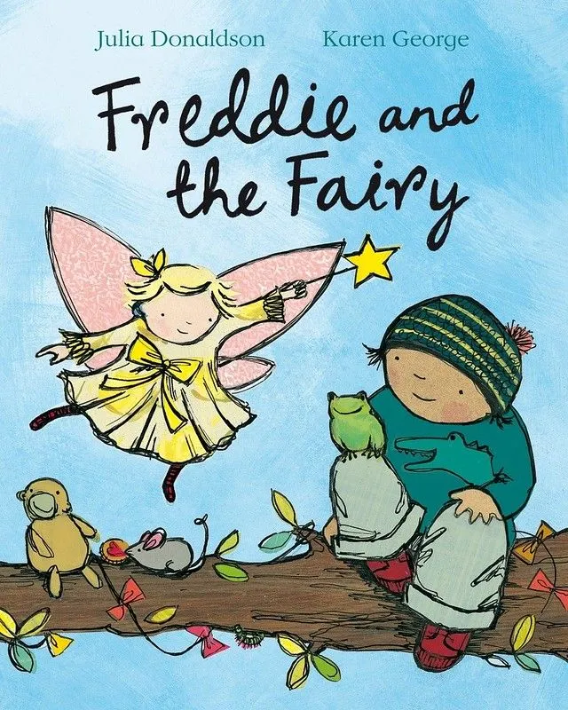Forside av Freddie And The Fairy: Freddie sitter på en tregren med noen dyr, og en fe er ved siden av ham på himmelen og peker på tryllestaven hennes.